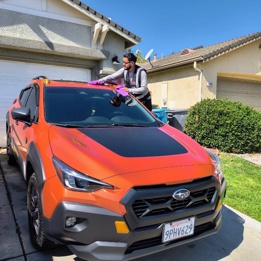 Professional detailer working on orange Subaru Crosstrek